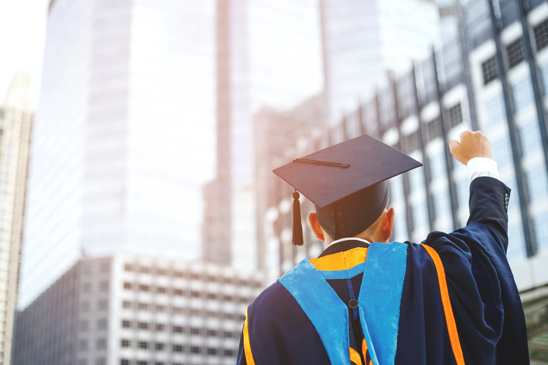 Graduate in Academic Regalia Lifting His Fist  